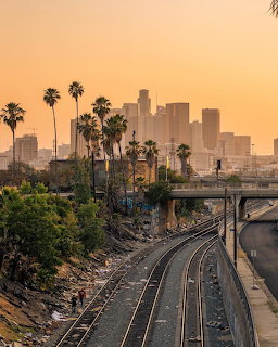 Los Angeles downtown skyline at sunset with palm trees and railroad tracks in foreground