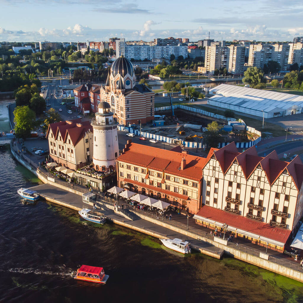 Aerial view of Kaliningrad waterfront buildings, lighthouse, boats, and river.