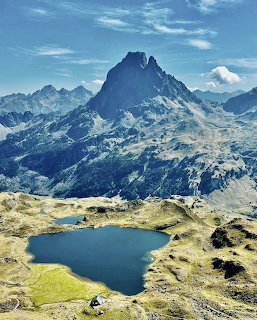 Alpine lake with jagged Pic du Midi d'Ossau mountain peak rising above Pyrenees range under blue sky