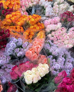Multiple bundles of colorful roses in various shades including orange, pink, purple, white and magenta