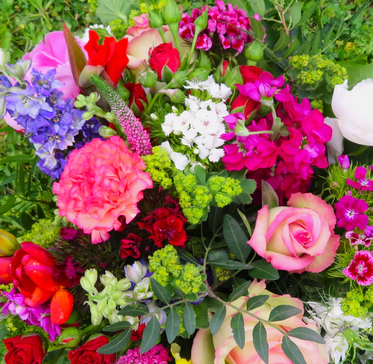 Colorful bouquet with pink roses, purple hyacinths, red flowers, white blossoms, and green leaves