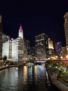 Chicago skyline at night along the river with illuminated buildings and bridge on Wacker Drive