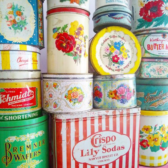Collection of vintage metal tins and containers with colorful floral patterns and retro brand labels