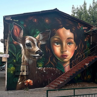 Colorful mural of a young girl and deer painted on the side of a building with stairs