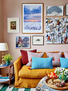 Living room with yellow sofa, colorful pillows, and gallery wall of framed artwork above