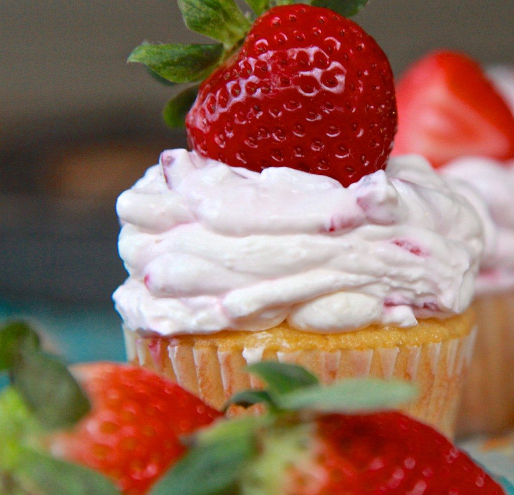 Cupcakes with white frosting and fresh strawberries on top