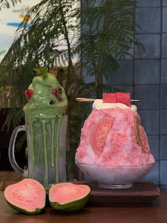 Two shaved ice drinks, one green and one pink, served with fresh watermelon slices on a wooden table