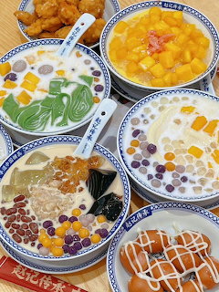 Overhead view of assorted Thai desserts in blue-trimmed white bowls with colorful toppings and coconut-based sweets