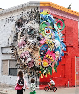 Large street art mural of a split animal face on a building with pedestrians walking by