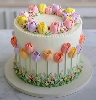 White frosted cake decorated with colorful buttercream tulips and flowers