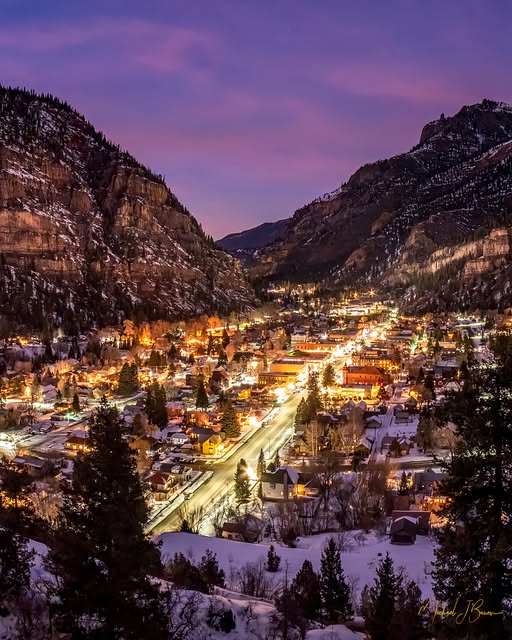 Snowy mountain town of Ouray Colorado at twilight with city lights glowing between steep canyon walls