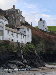 White and stone houses on a rocky coastal cliff above a small beach