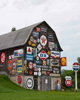 Old barn covered with colorful vintage gas station and oil company advertising signs