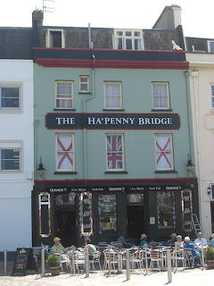 The Ha'penny Bridge pub building with outdoor tables and chairs on the street in front