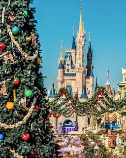 Cinderella Castle behind decorated Christmas tree at Disney theme park