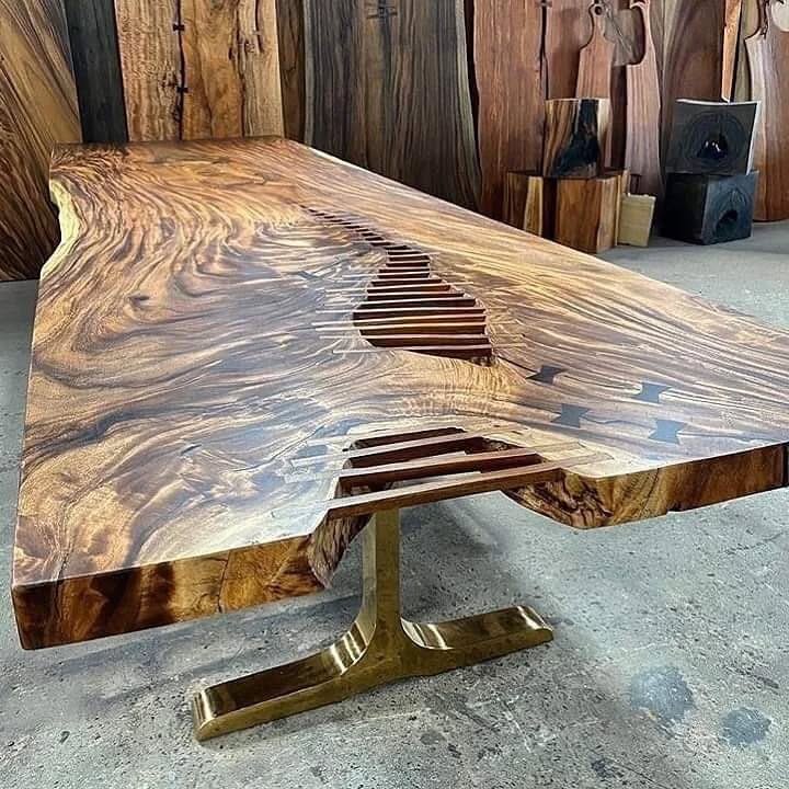 Live edge wood table with butterfly joints and natural grain patterns on metal pedestal base