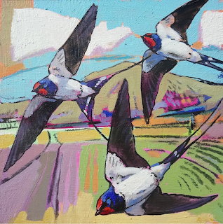 Three swallows with black wings and white bodies flying over a colorful patchwork countryside in an impressionist painting style