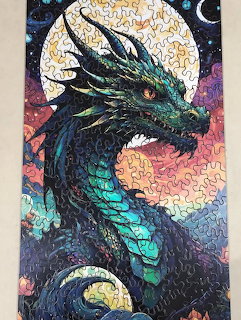 Detailed painting of a teal and black dragon in front of a full moon at night