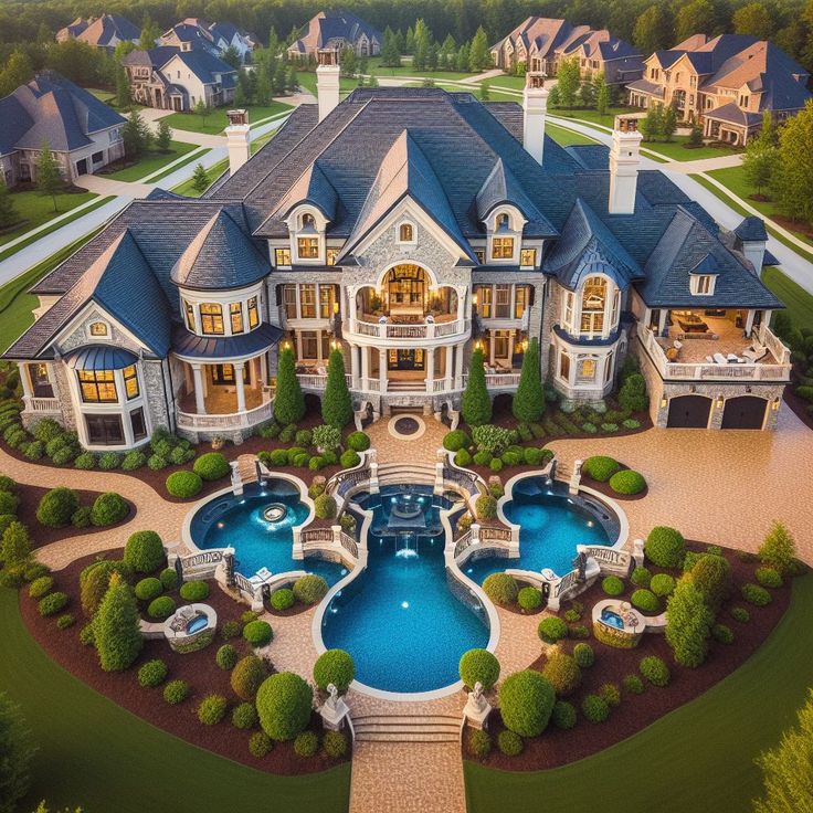 Aerial view of large beige mansion with blue pools and landscaped circular driveway