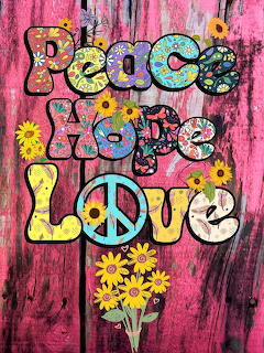Colorful Peace and Love lettering with flowers and a peace sign on a pink wood background