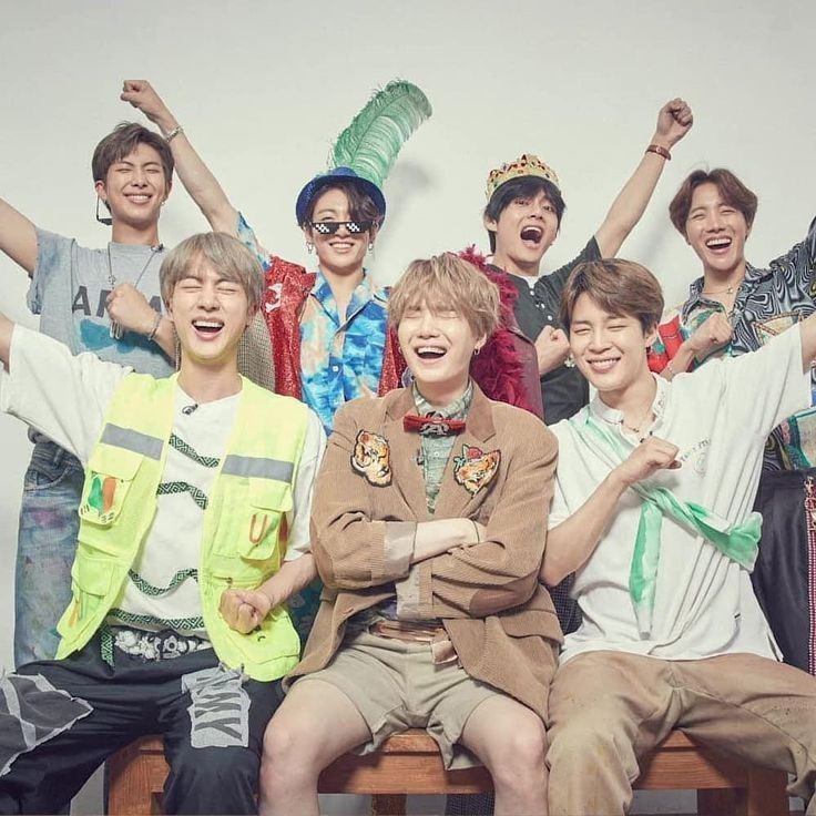 Six smiling young men in colorful casual clothes posing and cheering together