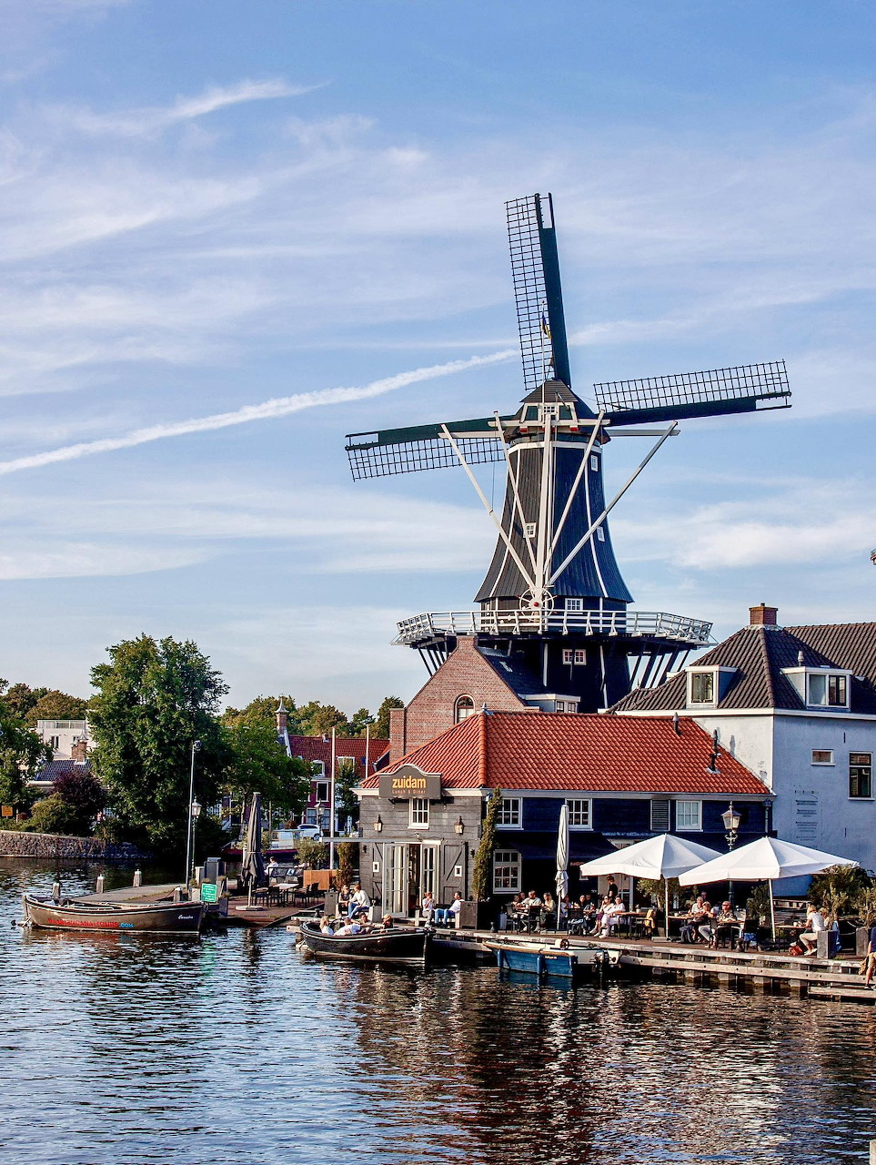 Traditional Dutch windmill beside a canal in Haarlem with waterside buildings and a mored boat