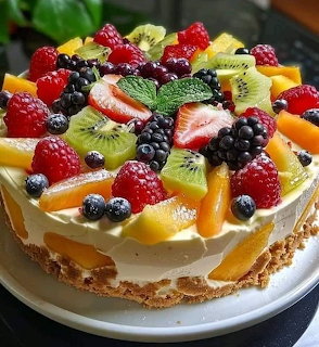 Cream cake topped with colorful fresh fruit including berries, kiwi, and mango slices with mint garnish