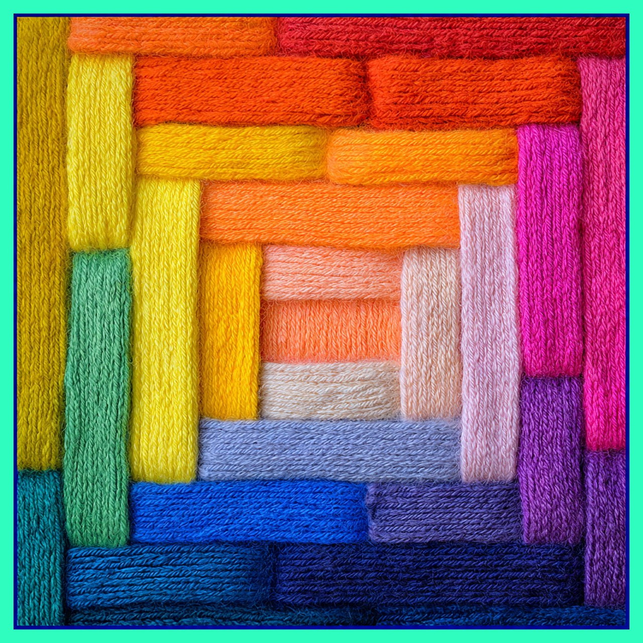 Concentric square spiral pattern made of colorful yarn skeins in rainbow gradient