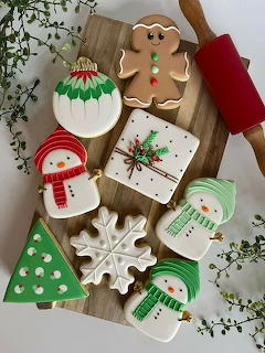 Assorted decorated Christmas cookies on wooden cutting board with festive shapes and icing