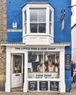 White corner fish and chip shop storefront with bay window and chalkboard signs