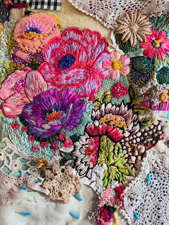 Colorful embroidered flowers and crocheted lace doilies arranged on textured fabric with intricate needlework details