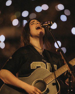 Billie Eilish singing into a microphone on stage at a concert