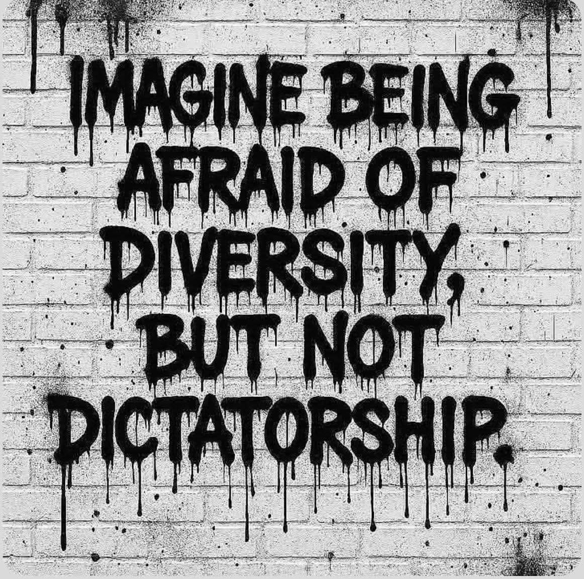 Black dripping graffiti message on a white brick wall about diversity and dictatorship