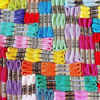Organized rows of multicolored embroidery thread skeins with labeled paper bands in rainbow arrangement