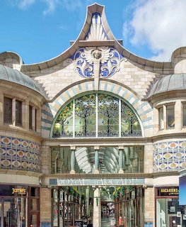 Ornate Art Nouveau entrance of Royal Arcade Norwich with decorative tiles and arched glass canopy