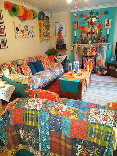 Bright living room with patchwork furniture, colorful quilts, turquoise walls, and eclectic bohemian decor