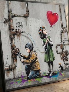 Framed wall art of a boy at a valve and a girl holding a red heart balloon beside rusty pipes