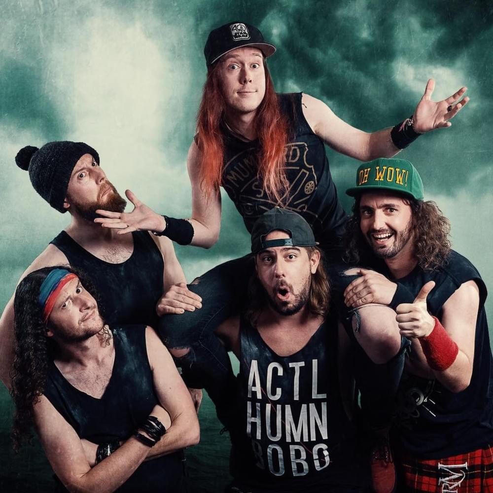 Five men in black shirts and caps pose together in a studio with a smoky green backdrop.