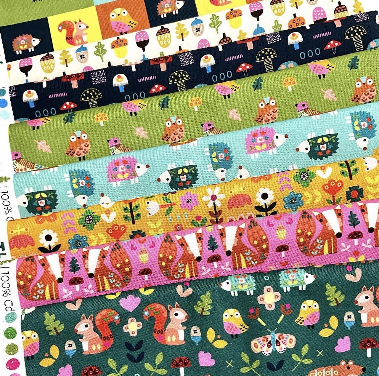 Nine horizontal strips of patterned fabric with cartoon characters, flowers, and mushrooms in vibrant colors