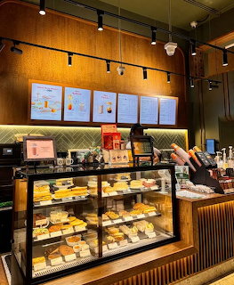 Cafe counter with glass display cases showing pastries and baked goods under warm lighting