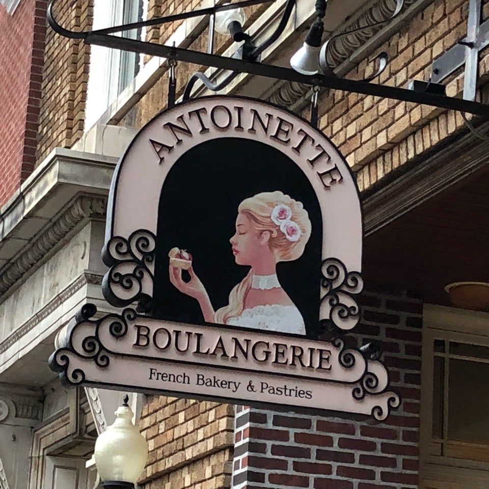 Decorative Antoinette Boulangerie sign with a woman illustration hanging on a brick building