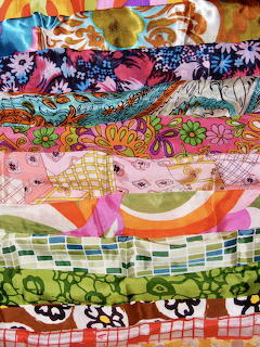 Stack of colorful vintage scarves with various floral and geometric patterns in bright retro colors
