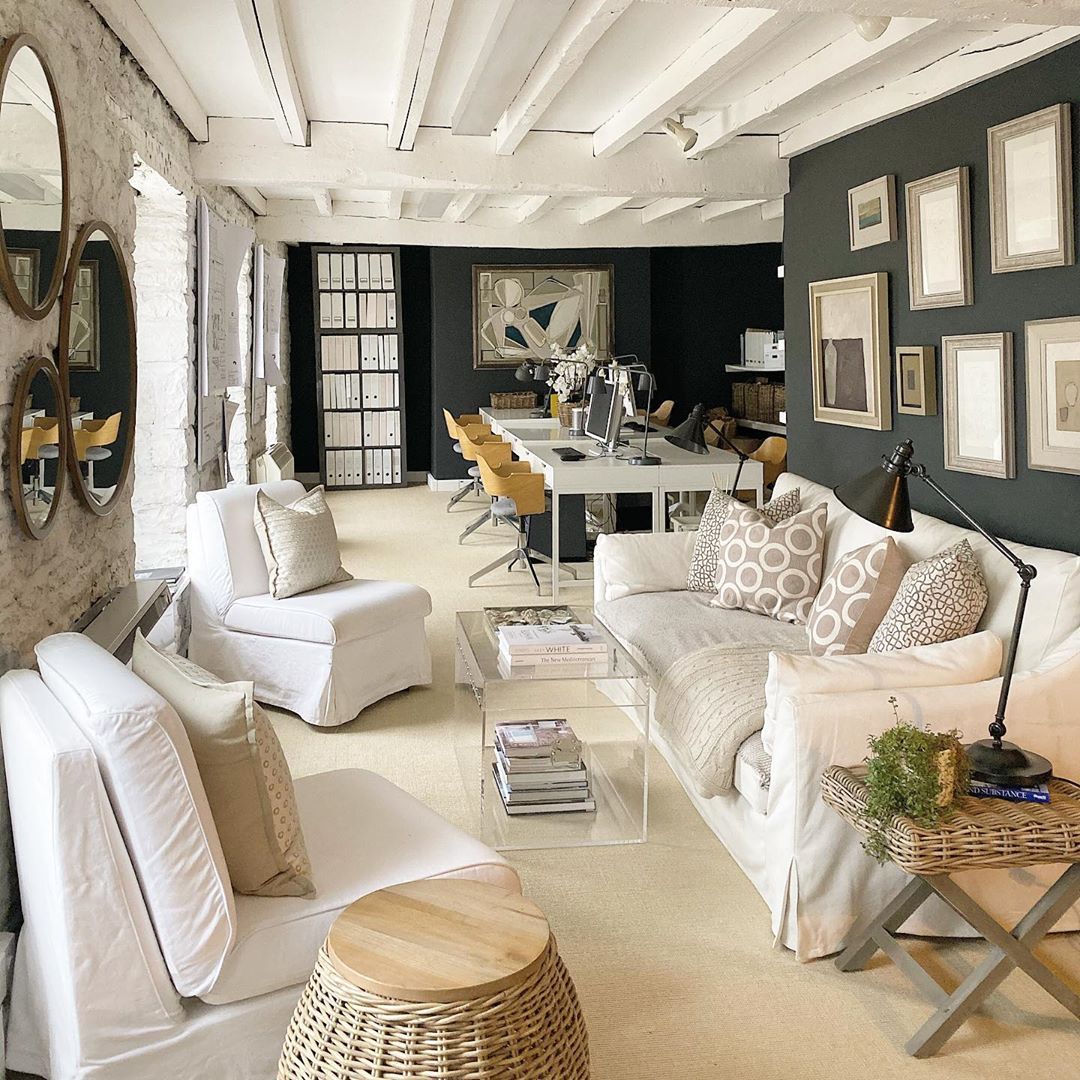 Spacious living room with white furniture, wooden beams, and dark feature wall with framed art