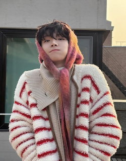 Person in striped cardigan and pink hoodie outdoors