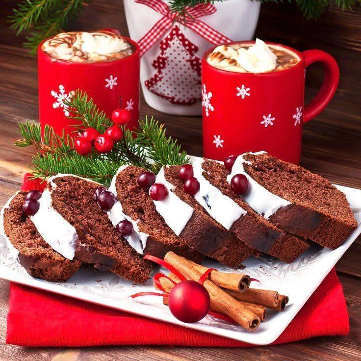 Chocolate cake slices with white frosting Christmas tree decorations, red mugs with hot cocoa, and holiday ornaments