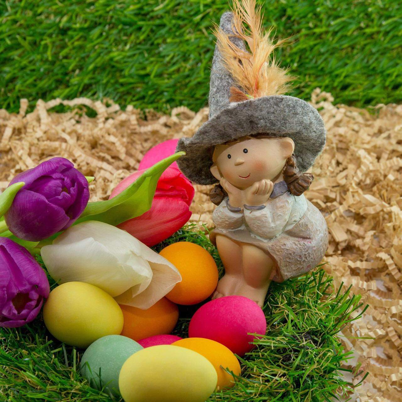 Easter bunny figurine with colorful tulips and painted eggs on grass