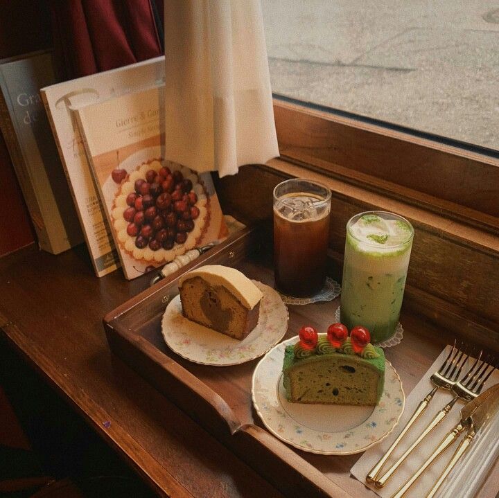 Matcha latte and iced coffee with slices of pound cake on a wooden table by a window