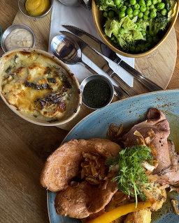 Roast meat with vegetables on blue plate, side dishes and greens on wooden table