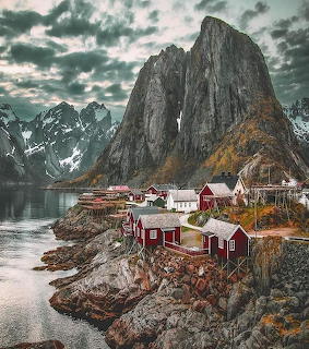 Red Norwegian fishing cabins at the base of steep mountain peaks in Reine, Lofoten Islands