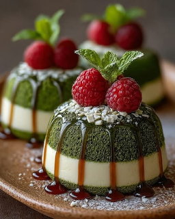 Green matcha panna cotta desserts with raspberries and mint garnish on a plate